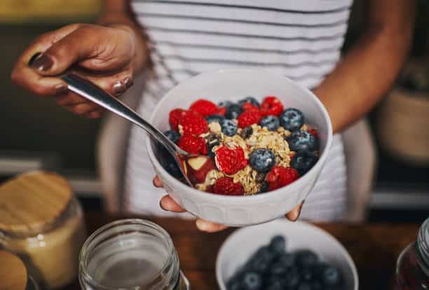 woman holding bowl of health grains and fruit